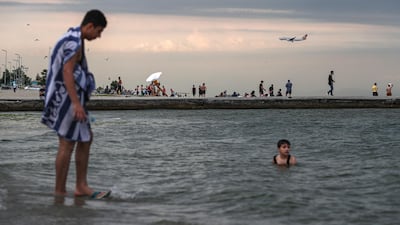 A Turkish Airlines plane prepares for landing as Syrian refugees enjoy their weekend at Menekse Beach, amid the ongoing pandemic in Istanbul, Turkey. EPA