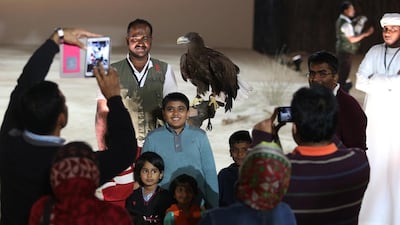 Members of the public take photographs with one of the hunting birds from the Al Ain Zoo after the Sky Show on Wednesday. Delores Johnson / The National
