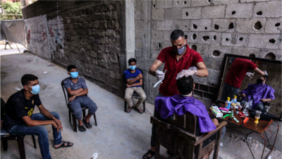 When barber shops in Gaza closed due to the pandemic, Sameh decided to set up shop outdoors in his neighborhood. Here, he tends to the children of his relatives and neighbors, while everyone maintains social distancing protocols. Photo by Samar Abu Elouf