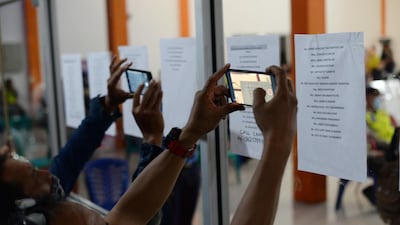A number of family members of Sriwijaya Air SJ 182 passengers using mobile phones take pictures of their relatives' names from notes attached on the window of an office as they wait news on their loved ones, at Pontianak Supadio International Airport, in Pontianak, West Kalimantan, Indonesia. EPA