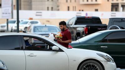 A cafeteria employee delivers karak and snacks to a customer in their car in Sharjah. Chris Whiteoak / The National