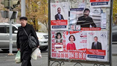People walk past election posters in Yerevan on December 6, 2018, days before early parliamentary elections. AFP