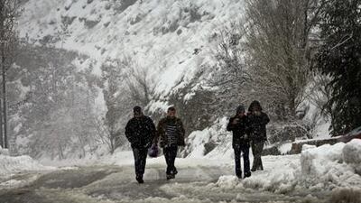 Lebanese citizens make their way through snow unable to find transport on the Beirut-Damascus highway, in Sawfar mountain, Lebanon. AP Photo/Hussein Malla