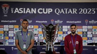 Jordan's Salem Al Ajalin, left, and Qatar's Hassan Al Haydos pose next to the Asian Cup trophy ahead of Saturday's final. AP