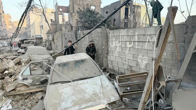People walk past damaged cars and rubble at the site of the Israeli air strike in Bachoura. AFP