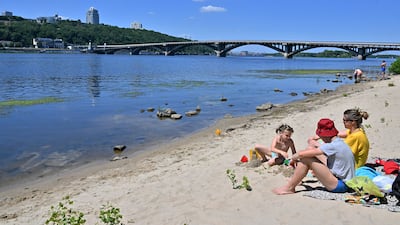 A family on the shores of the Dnipro river that runs through the Ukrainian capital of Kyiv on July 2, 2022. AFP