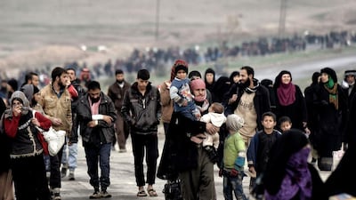 Iraqi families walk down a road as they flee Mosul on March 3, 2017, during an offensive by security forces to retake the western parts of the city from ISIL fighters. Aris Messinis / AFP / AP