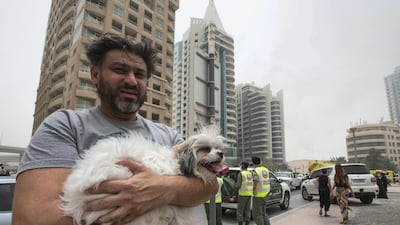 A resident from the burning Zen Tower takes care of his dog. Leslie Pableo for The National