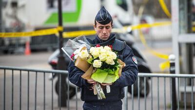 A police officer carries flower tributes given by a pedestrian at the site of the attack on a kosher market in Paris on January 10. David Ramos/Getty Images