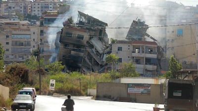 People drive next to a building, targeted in an Israeli air strike in Beirut's southern suburbs. AFP