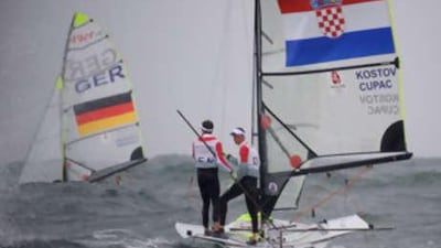 Sailors Jonas Warrer and Martin Kirketerp Ibsen of Denmark wait near the finish line aboard the 49er class boat from Croatia after the medals race. Protests were filed for the team competing aboard another team's boat.