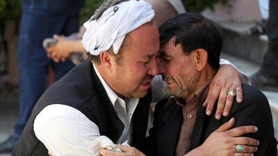 Afghan men mourn during the funeral of their relatives after a wedding suicide bomb blast in Kabul. REUTERS