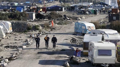 French CRS riot police walk past debris from makeshift shelters on October 28, 2016, as they patrol during the dismantlement of the camp called the "Jungle" in Calais, France. Pascal Rossignol / Reuters