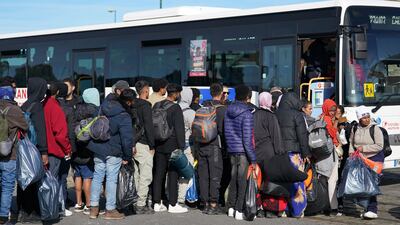 Migrants hold their belongings as they queue to board a local bus in Gravelines, France. PA