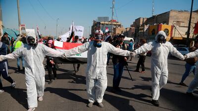 Anti-government protesters wear hazmat suits and gas masks during a protest to condemn the militia attack on Najaf protesters late on Wednesday night, in Tahrir Square, Baghdad, Iraq. AP Photo