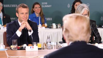 French President Emmanuel Macron looks at US President Donald Trump at the Gender Equality Advisory Council meeting on June 9, 2018. EPA