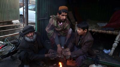 Afghan men gather around a fire to beat the cold in Jalalabad, Afghanistan. EPA