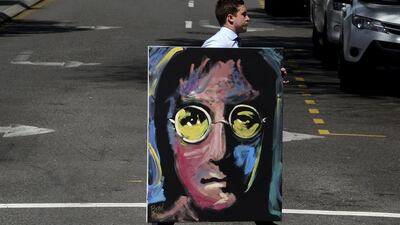 A man carrying a portrait of music legend John Lennon crosses a road in central Brisbane, Queensland, Australia. Lennon, the late musician whose birthday was on October 9, will be celebrated in a new graphic novel of his life story, to hit shelves in 2017. EPA