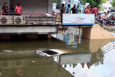 People look at a submerged car in a flooded commercial complex after heavy rains in Ahmedabad on July 11. AFP