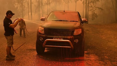 A local man hoses down fire retardant from a vehicle during a bushfire in Werombi, 50km south west of Sydney, Australia. EPA