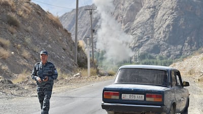 A police officer walks on a road as smoke rises after an explosion during a de-mining operation near the Kyrgyz-Tajik border in the village of Ak-Say, some 1000 kilometres from Bishkek, on September 21, as the worst violence the two ex-Soviet countries have seen in years broke out last week on their contested border. AFP