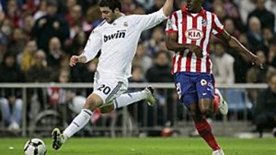 Real Madrid's Gonzalo Higuain, left, scores Real's third against Atletico as Luis Perea looks on.
