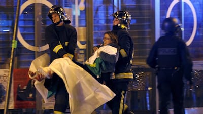 French fire brigade members aid an injured individual near the Bataclan concert hall following fatal shootings in Paris, France, on Friday. Christian Hartmann / Reuters
