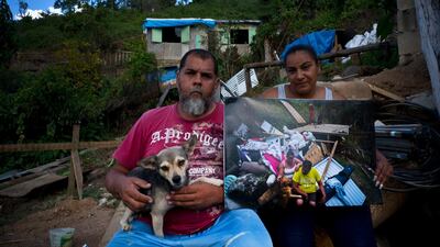 William Fontan Quintero and his wife Yadira Sostre pose with a printed photo of them taken on September 30, 2017, when they sat amid the rubble of their home destroyed by Hurricane Maria. "We don't have time to build anything safe without help," said Quintero.