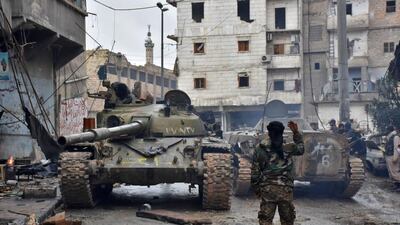 A pro-government fighter gestures to tanks as they patrol Aleppo on December 14, 2016. George Ourfalian/AFP