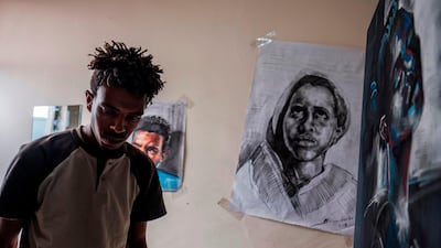 Eritrean artist Nebay Abraha, 23, walks past his paintings hung on the wall of his room and studio in Addis Ababa. AFP