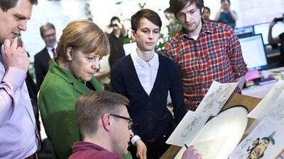 Angela Merkel watches an artist during a tour of local start-ups in Berlin. The German capital is gaining a reputation as a technology hub. Thomas Peter / AFP