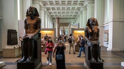 Visitors wearing face masks walk through the Egyptian exhibition as the museum reopened to the public after being closed for 163 days due to Covid lockdowns