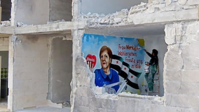 Artist Aziz al-Asmar paints a mural wishing for the well-being of German Chancellor Angela Merkel, who is in quarantine after being treated by a doctor who tested positive for coronavirus, inside a damaged building in the town of Binnish in Syria's northwestern Idlib province. AFP