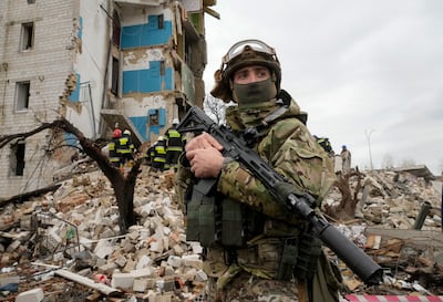 A Ukrainian soldier stands against the background of an apartment house ruined in the Russian shelling in Borodyanka, Ukraine, Wednesday, Apr. 6, 2022. (AP Photo / Efrem Lukatsky)