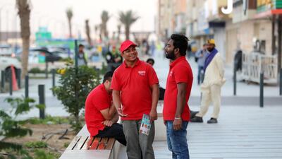 Cafeteria workers chat outside the cafe's as they wait to be beckoned by a car horn in Sharjah. Chris Whiteoak / The National