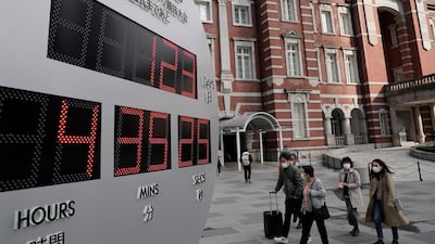 Pedestrians wearing masks walk past a countdown clock displaying the time until the opening of the Tokyo Olympic Games outside Tokyo railway station. Japanese Prime Minister Shinzo Abe said postponement of Games is a genuine possibility. EPA