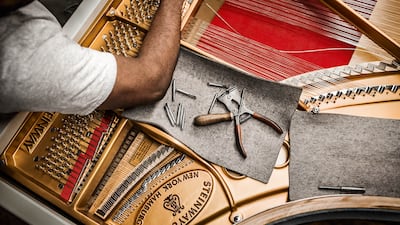 A technician fits strings into the cast-iron frame of a concert grand. Photo: Steinway & Sons
