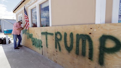 John Murray attaches a US flag to a sign reading "Bet They Blame Trump" at his business damaged in the wake of Harvey in Rockport, Texas. Murray created the sign in hopes president Donald Trump would visit Rockport during his Texas visit, but he did not expect him to make the trip. Eric Gay / AP Photo