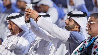 Sheikh Mansour bin Mohamed bin Rashid enjoys the ceremony, taking pictures on his phone. Ryan Carter / the Crown Prince Court