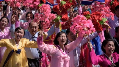 Participants wave flowers as they march past a balcony from where North Korea's leader Kim Jong Un was watching, during a mass rally on Kim Il Sung square in Pyongyang. AFP
