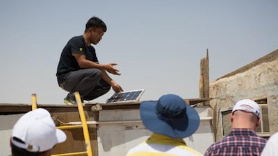 Monyati Initiative volunteers help to install solar panels at a farm near Mirfa, Abu Dhabi emirate. The solar panels connect to a fan, two lamps and a mobile phone charger in each of the 55 farms the project will eventually cover. Courtesy Amelia Johnson