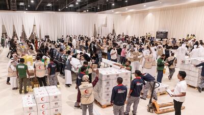 Rows of volunteers and charity workers pack and stack the boxes of aid for Gazans, at Al Rimal Hall in Dubai.