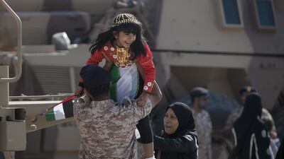 Sheikha Rafat Bawazir gets a lift up onto an army vehicle while she and her family attend a military display along the Corniche Road in Abu Dhabi. Silvia Razgova / The National