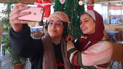 Women take a selfie with a Christmas tree at a coffee shop in Gaza city, in the Gaza Strip. AFP