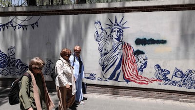 Iranian women walk past anti-US murals outside the former US embassy in Tehran. AFP