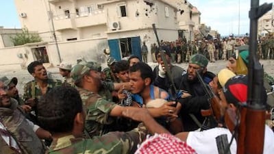 NTC troops capture a wounded loyalist fighter during battles in Sirte. NTC forces said they finally captured the city today.
