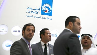 Visitors talk near the Adnoc stall at Adipec. Silvia Razgova / The National