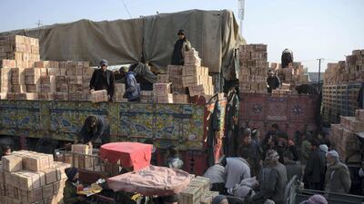 Afghan labourers unload crates of fruit from a truck at a fruit market in Mazar-i-Sharif on January 26, 2018. / AFP PHOTO / FARSHAD USYAN