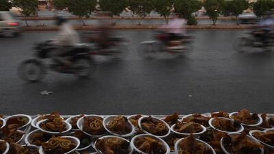 Pakistan motorcycle riders in Karachi drive past plates of food for iftar. Asif Hassan / AFP Photo
