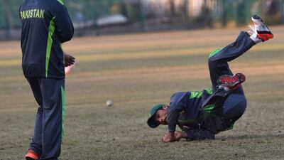 Pakistani cricketer Mohammad Amir dives to catch the ball during a training session in Lahore on Thursday. Arif Ali / AFP / December 24, 2015